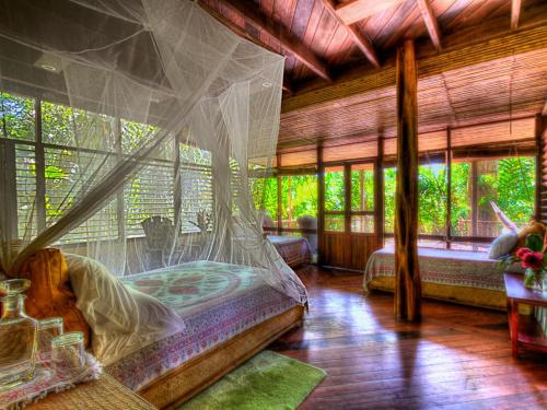 a bedroom with a bed with a mosquito net at Iguana Lodge Beach Resort in Puerto Jiménez