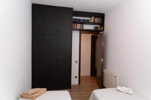 a bedroom with two beds and a black cabinet at GranVia Fira Apartment in Hospitalet de Llobregat