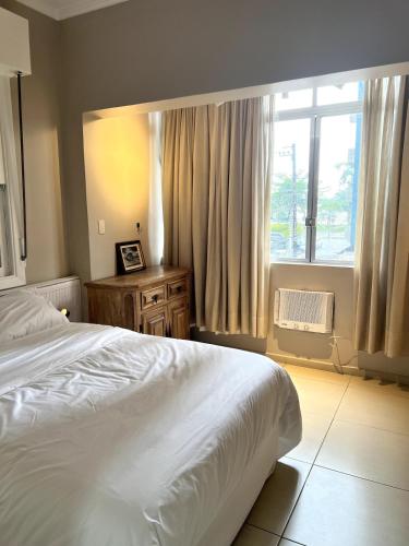 Un dormitorio con una cama blanca y una ventana. en Cozy, comfortable ocean view apartment for 4 people, en Santos