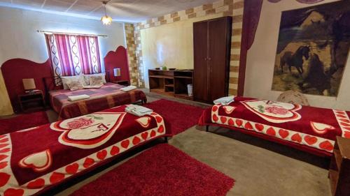 two beds in a room with red carpet at Rocky Mountain Hotel in Wadi Musa