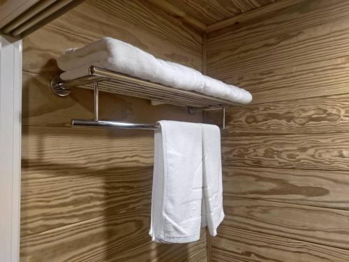 Island Paradise Resort Club في كورور: حمام به مناشف بيضاء على رف للمناشف