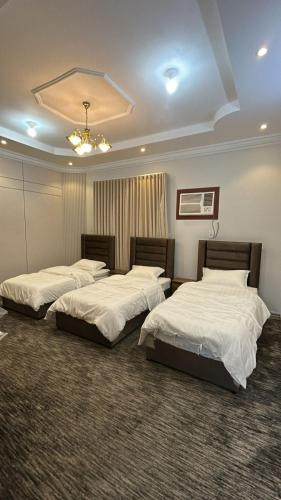 two beds in a room with white sheets at شقة ثلاثة غرف نوم وصالة in Al Baha