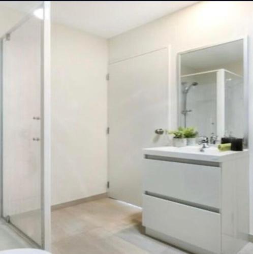 a white bathroom with a sink and a mirror at Cozy Ensuite Room in Auckland