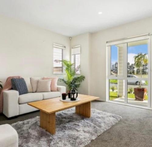 a living room with a couch and a coffee table at Cozy Ensuite Room in Auckland