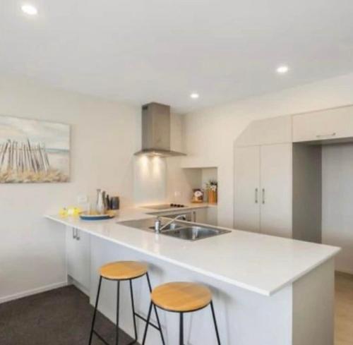 a kitchen with a white counter and two stools at Cozy Ensuite Room in Auckland