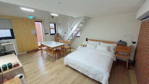 a bedroom with a bed and a table and a staircase at 鹿厝回家-包棟民宿 in Lugang