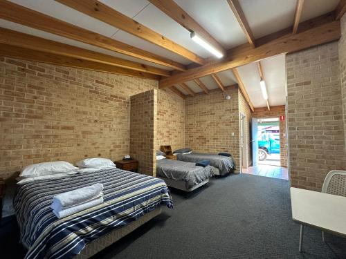 Un dormitorio con dos camas y una pared de ladrillo. en Nannup Hotel Motel, en Nannup