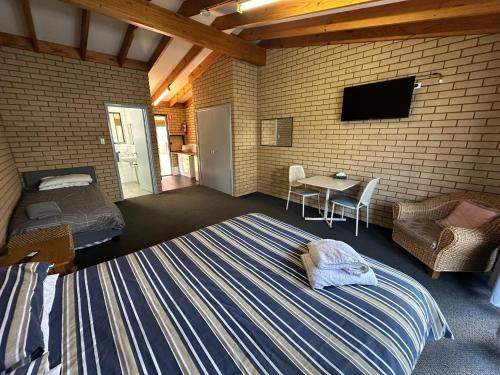 Un dormitorio con una cama, un televisor y una mesa. en Nannup Hotel Motel, en Nannup