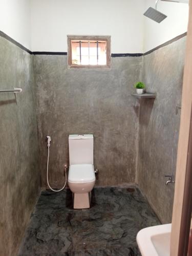 a bathroom with a toilet and a sink and a window at Breeze House in Hikkaduwa