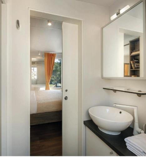 a white bathroom with a sink and a bed at Victoria Mobilehome in Padova Premium Camping Resort in Banjol