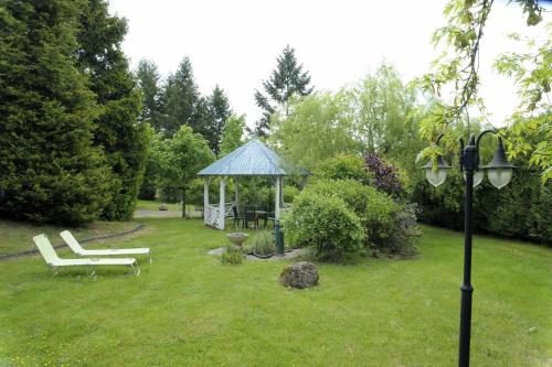 a gazebo and a bench in a yard at Hôtel Logis Le Relais De La Poste in Neuvéglise
