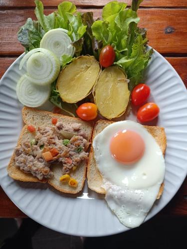 a plate of food with an egg and a salad at ม่วนใจ๋ปันสุข โฮมสเตย์แอนคาเฟ่ Muanjai punsuk homestay and cafe in Chom Thong
