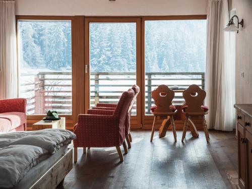1 Schlafzimmer mit 2 Stühlen und einem großen Fenster in der Unterkunft Frida am Wald in Rasùn di Sotto