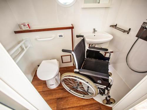 a wheelchair in a bathroom with a sink and a toilet at Floating Apartments at Rechlin Harbor by Kuhnle-Tours in Rechlin