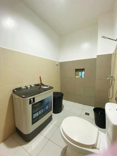 a bathroom with a toilet and a tv in it at Marinduque Apartment in Tagum