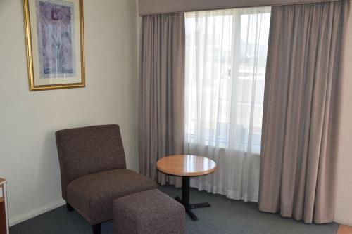 a room with a chair and a table and a window at Best Western Coachman's Inn Motel in Bathurst