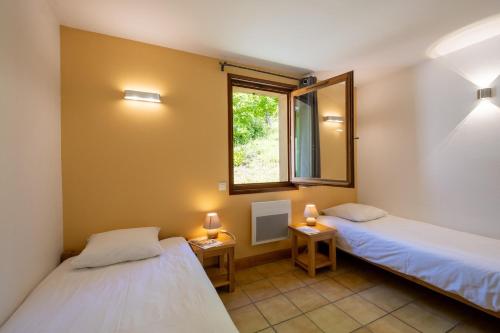 two beds in a room with a window and two lamps at Gîte Logement 4/6 personnes - Village de gites des Vignes in Les Vignes