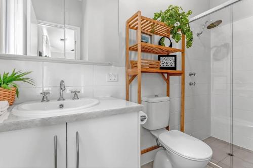 a white bathroom with a toilet and a sink at Reef Retreat - Modern Beach House Sanctuary in Port Noarlunga