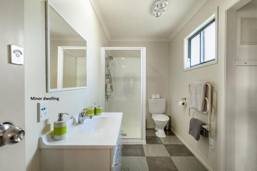 a white bathroom with a sink and a toilet at Hearty Acres Farm Cottage in Auckland