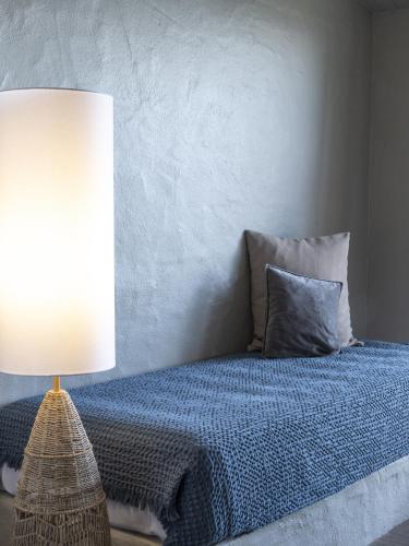 a bedroom with a bed with a blue blanket and a lamp at Hotel Punta Lara Noirmoutier in La Guérinière