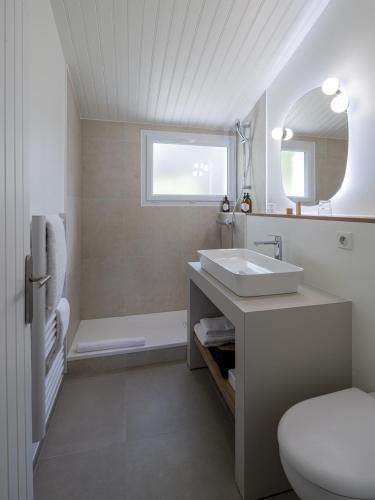 a white bathroom with a sink and a tub at Hotel Punta Lara Noirmoutier in La Guérinière
