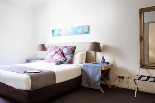 
a bedroom with a bed and a lamp at Hotel Richmond on Rundle Mall in Adelaide
