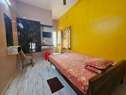 a bedroom with a bed with a yellow wall at Monalisa Lodge in Vishnupur