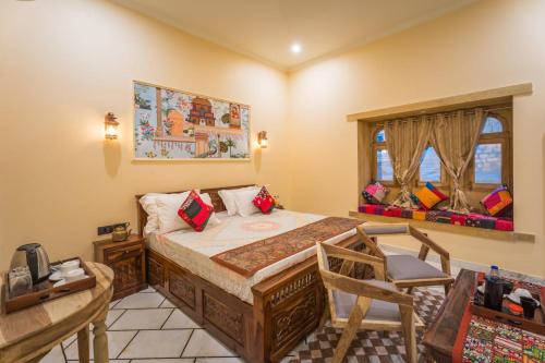 a bedroom with a bed and a chair and a window at The Second Home Jaisalmer in Jaisalmer