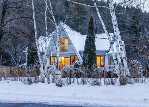a house with lights on in the snow at Bord de Fleuve - Spa - La Presqu'ile in Saint-Nicolas