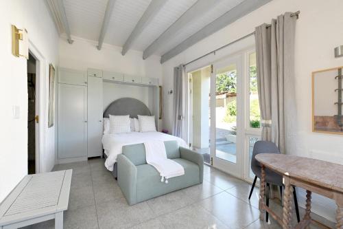 a bedroom with a bed and a chair and a table at The Little Vineyard Cottage in Franschhoek