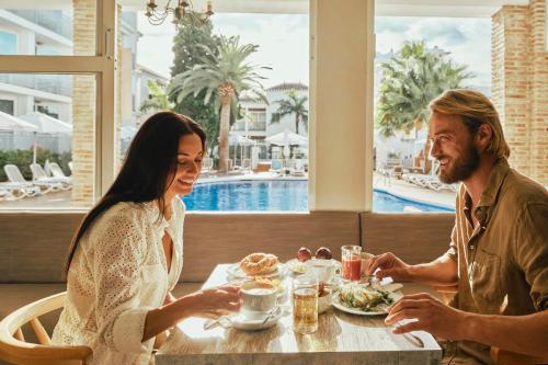 Hotel Villa Flamenca في نيرخا: يجلس رجل وامرأة على طاولة لتناول الطعام