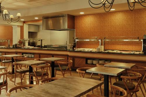 Hotel Villa Flamenca في نيرخا: مطعم مع طاولات وكراسي ومطبخ