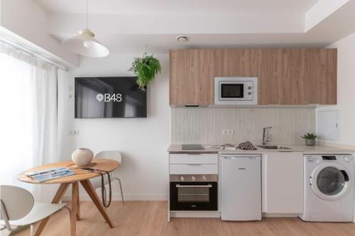 Una cocina con electrodomésticos blancos y una mesa con sillas. en B48 Bilbao Abando, en Bilbao