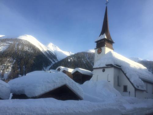 a church covered in snow with mountains in the background at Ferienapartment Weitsicht in Biel