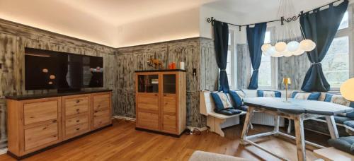 a living room with a tv and a table and a couch at Forsthaus Faistenau in Hintersee