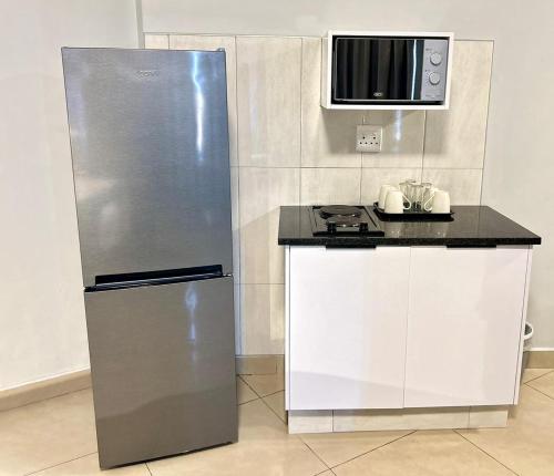a kitchen with a stainless steel refrigerator and a microwave at Bayside Self Catering and Hotel 14 Monty Naicker Pinestreet Durban in Durban