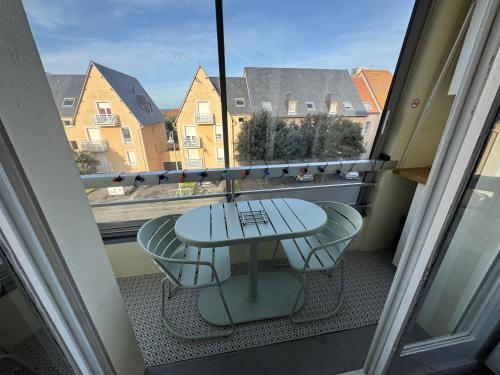 a balcony with a table and chairs and a window at La parenthèse bleue, loggia et parking in Courseulles-sur-Mer