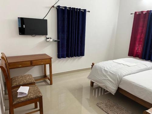 a bedroom with a bed and a desk and a tv at Mulberry homestay Munnar in Anaviratty