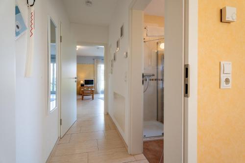 een gang met inloopdouche en een badkamer met witte muren bij Casa Mia by K A M E L U in Gengenbach