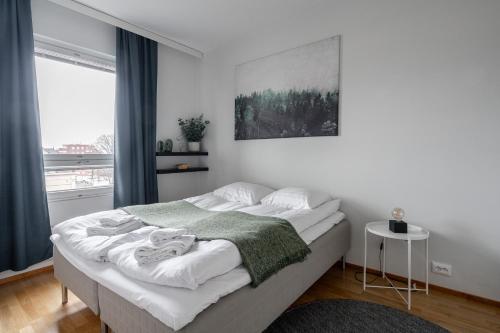 ein weißes Schlafzimmer mit einem großen Bett und einer grünen Decke in der Unterkunft "ESPA" - Modern 1BR Apartment with Sauna, Balcony & Free Parking in Tampere
