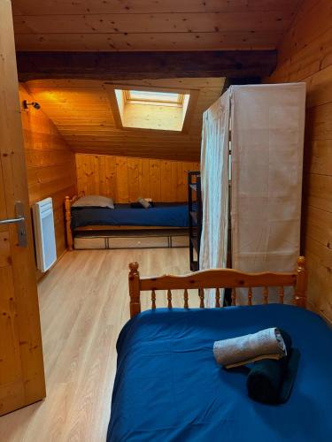 ein Schlafzimmer mit einem Bett in einer Holzhütte in der Unterkunft La Ruche, Maison chaleureuse de 5 personnes in Aigueblanche