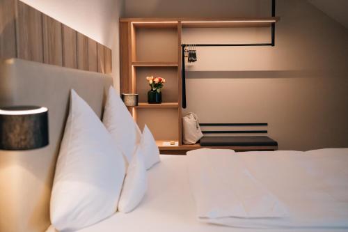 a bedroom with a white bed with white pillows at Klostermaier Hotel & Restaurant in Icking