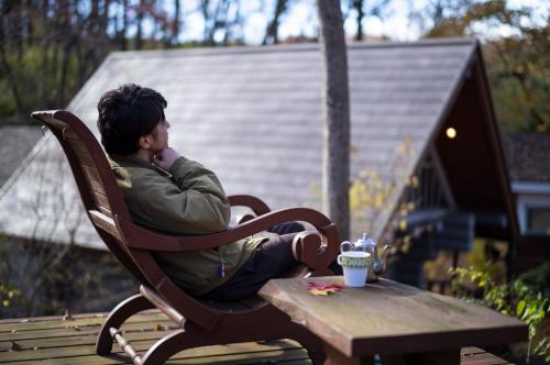 a man sitting on a bench with his head on a table at ログコテージ茶臼の森 in Nasu