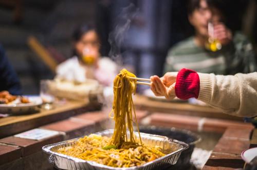 a person holding a chopstick in a pan of food at ログコテージ茶臼の森 in Nasu