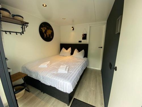 a bedroom with a bed with white sheets and a clock at Houseboat Uitgeest with Air Conditioning | 4 people in Uitgeest