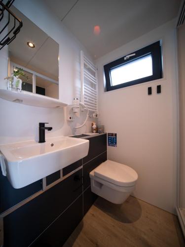 a bathroom with a sink and a toilet and a window at Houseboat Uitgeest with Air Conditioning | 4 people in Uitgeest