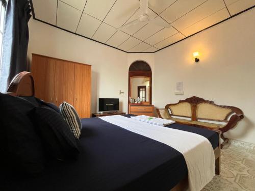 a bedroom with a large bed and a television at RIVINSON Negombo in Negombo
