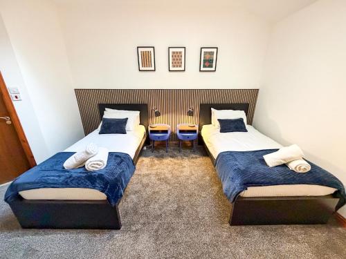 two beds in a room with two chairs at Core Citi Lets, Guild Street Rooms in Aberdeen