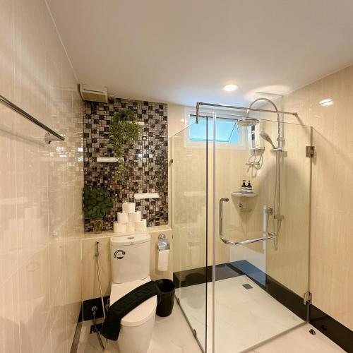 a bathroom with a glass shower and a toilet at Elegant Modern White Suite in Chiang Mai