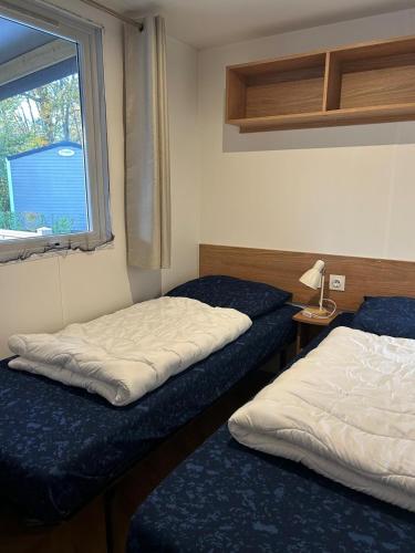 two beds in a small room with a window at Chalet Aventura 1-6 pers- 3 slaapk- 2 badk- Berging- Inchecken al vanaf 13 uur - incl gebruik koffie en thee in Lauwersoog